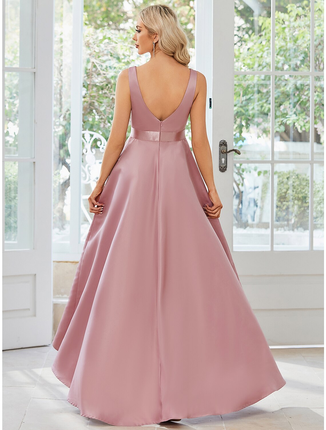 Side view of a woman in a sleeveless A-line ruffled satin dress.