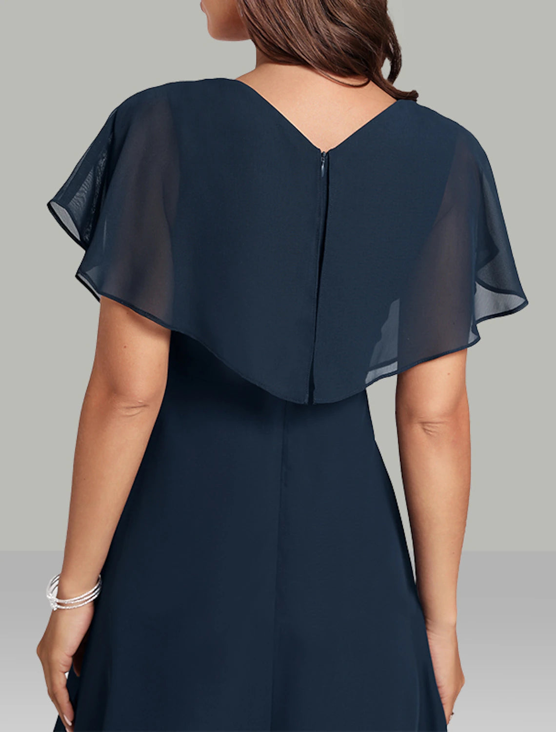 Side view of a woman in a navy chiffon A-line dress, showcasing the flowy skirt and sheer flutter sleeves.