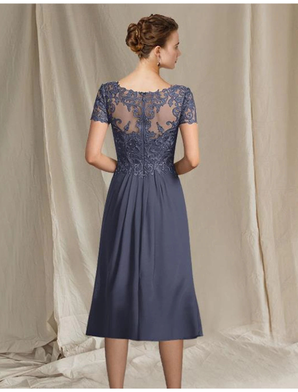 Back view of a woman in an A-line chiffon lace mother of the bride dress with pleats.