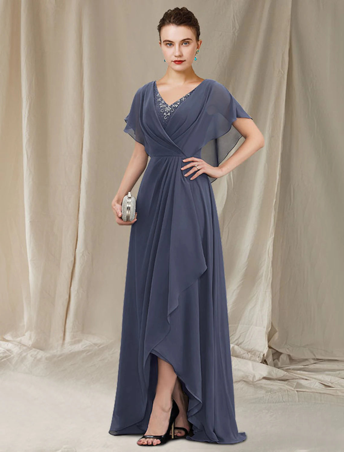 Full-length view of an elegant A-line V-neck short sleeve mother of the bride dress with a high-low hem and lace ruffles.