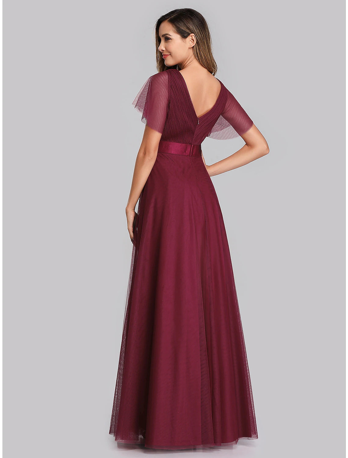 Model in a dark blue A-line chiffon gown, showcasing the V-back and ruched details.