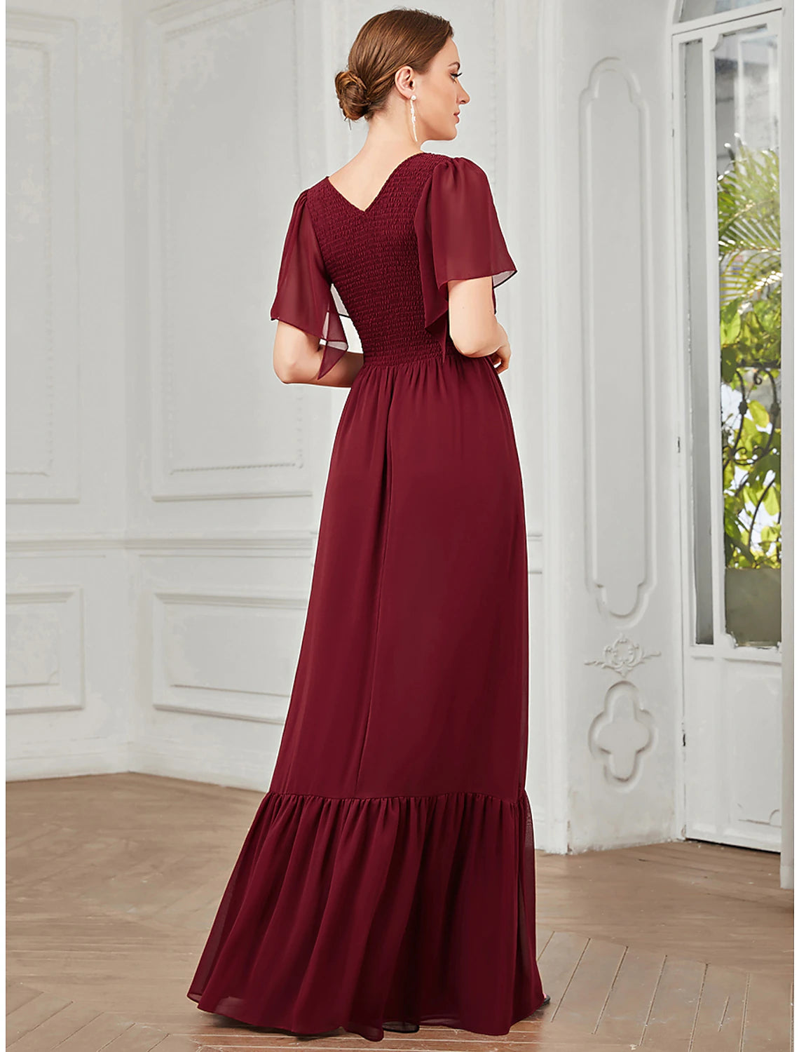 Back view of a woman in an elegant A-line V-neck short-sleeve chiffon gown.