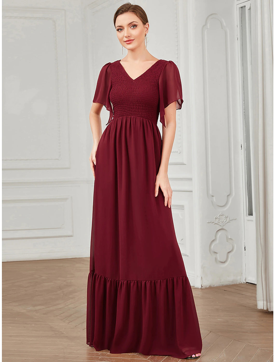 Side profile of a woman showcasing the pleated detail of a floor-length chiffon dress.