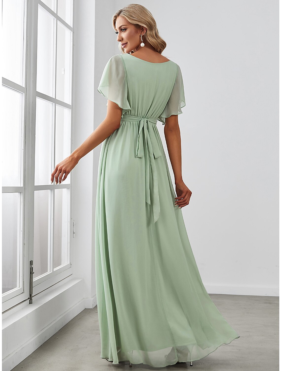 Back view of a model in a solid color A-line V-neck short sleeve ruffled chiffon bridesmaid dress.