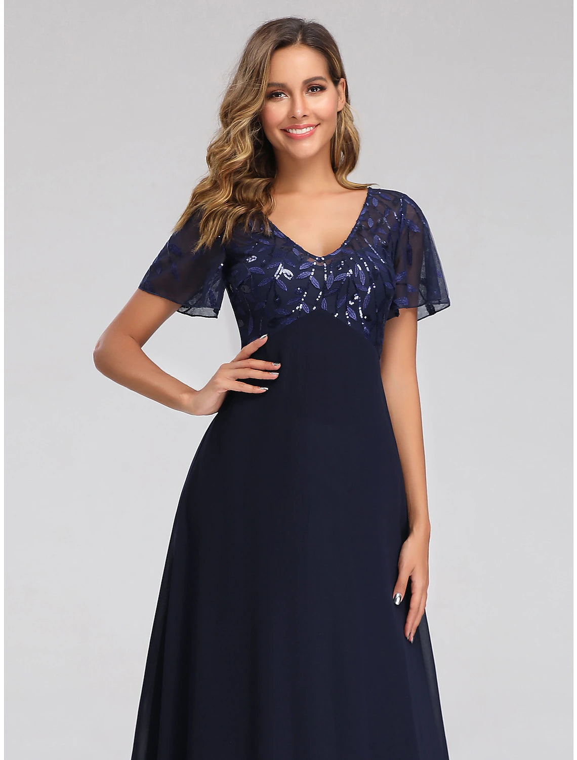 Side profile of a model showcasing the elegant floor-length sequin tulle dress.