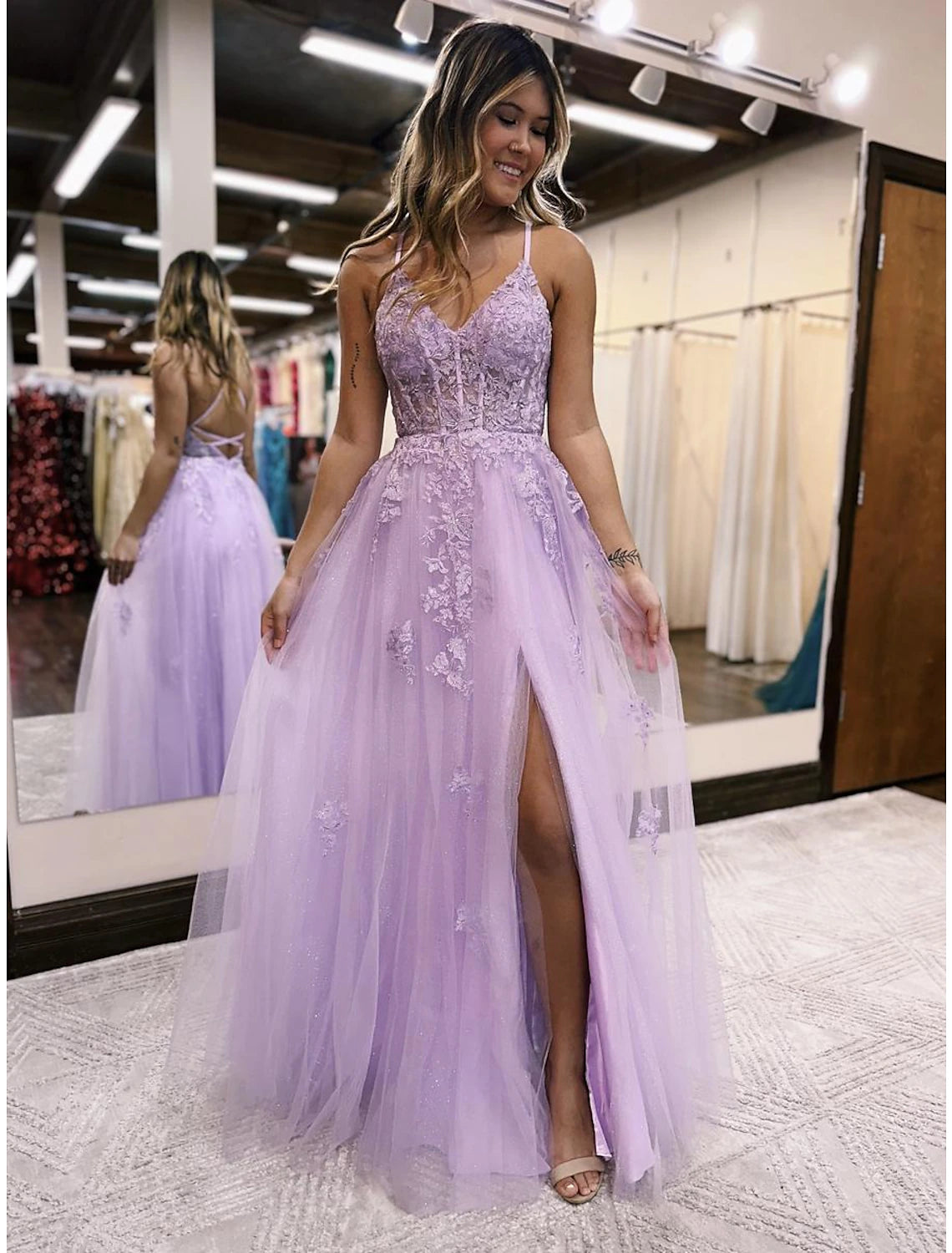 Model wearing a floor-length A-line V-neck tulle evening gown with an open back, beading, and a side slit.