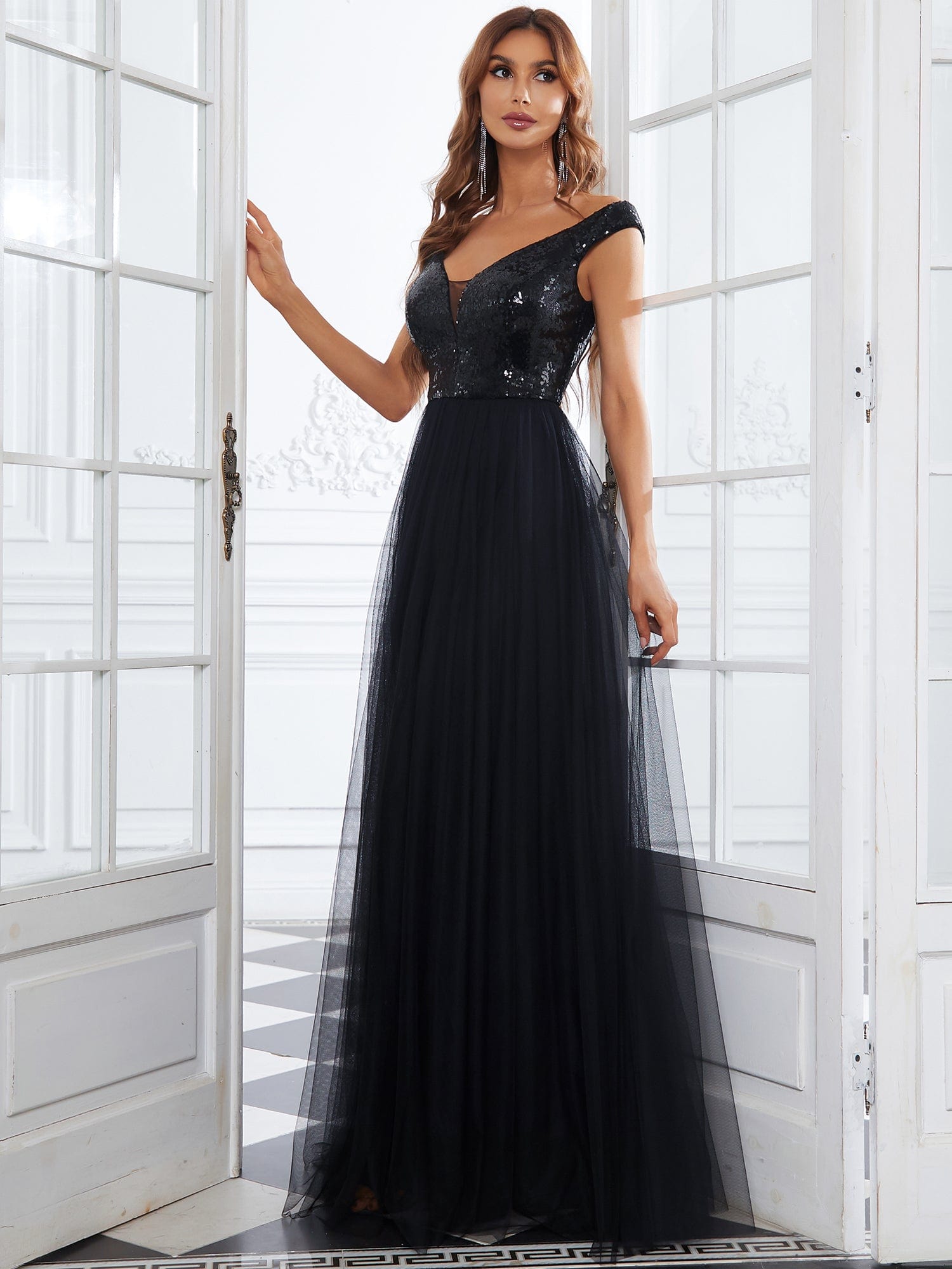 Model wearing a black A-line sequin off-shoulder maxi tulle dress.