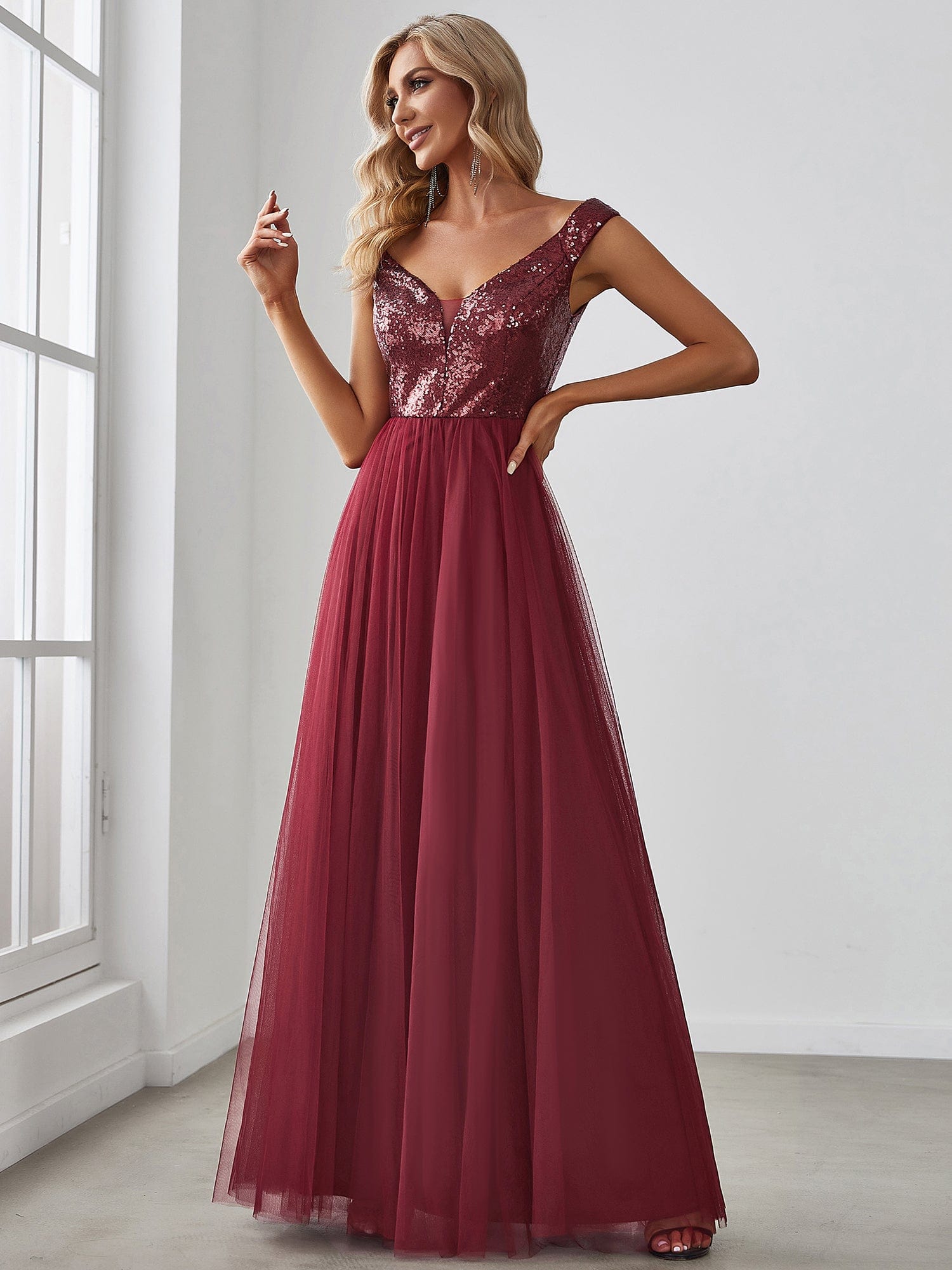 Model wearing a burgundy A-line sequin off-shoulder maxi tulle dress.