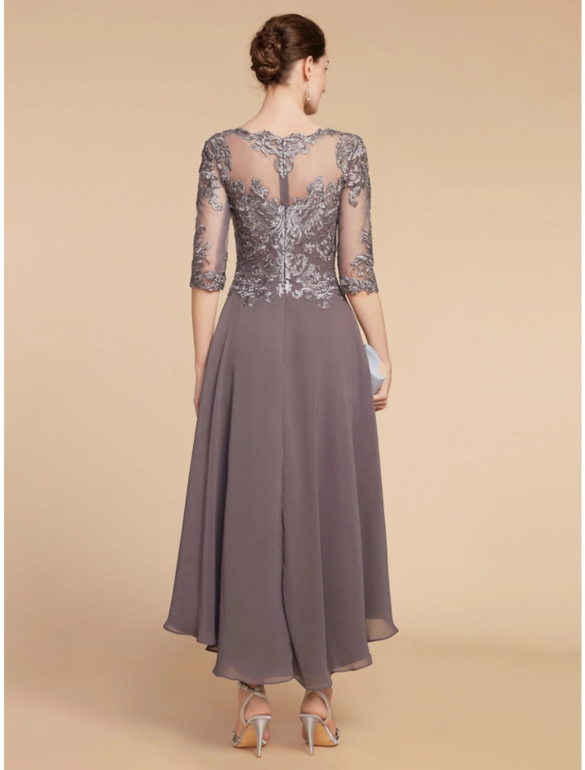 Back view of woman in A-line dress, showing ruched details and flowing asymmetrical skirt.