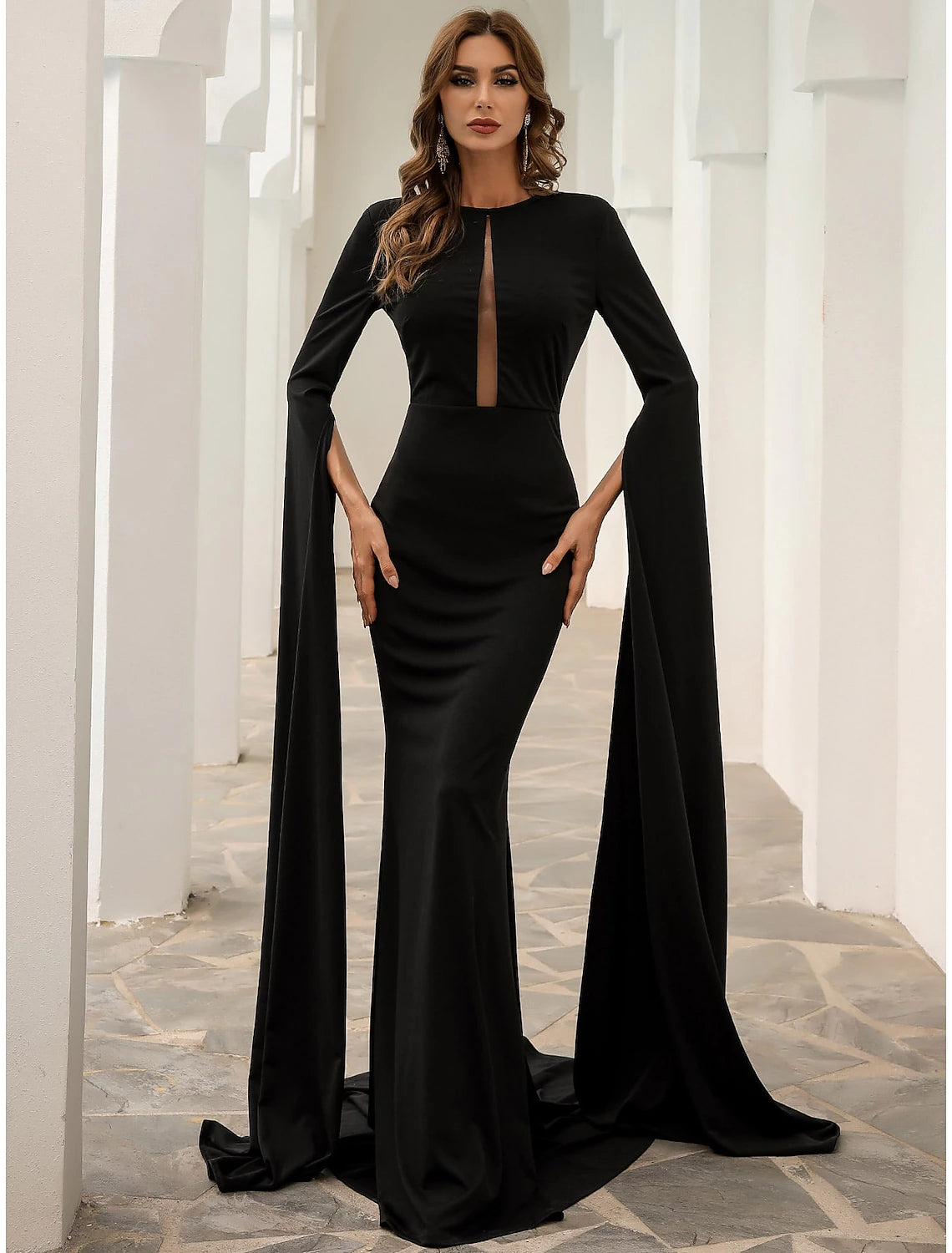 Full-length view of a woman wearing the elegant black mermaid trumpet evening gown with long sleeves and jewel neck.