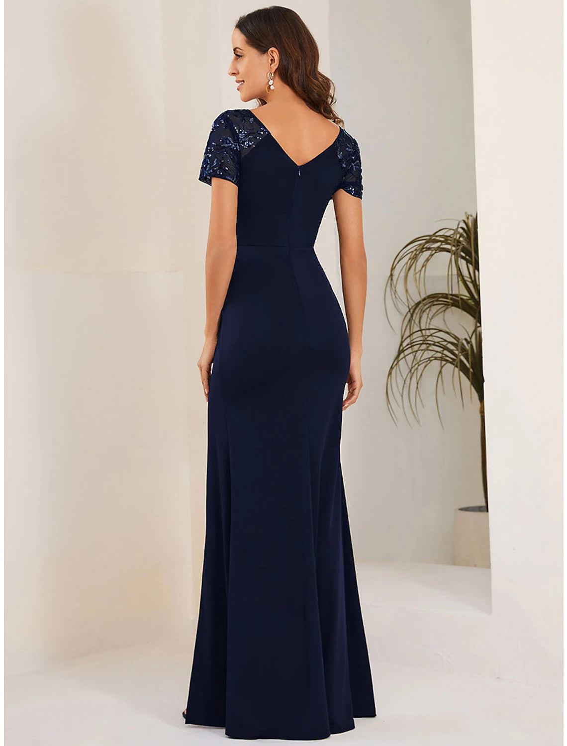 Back view of a woman in a black mermaid trumpet gown, showing the elegant silhouette.