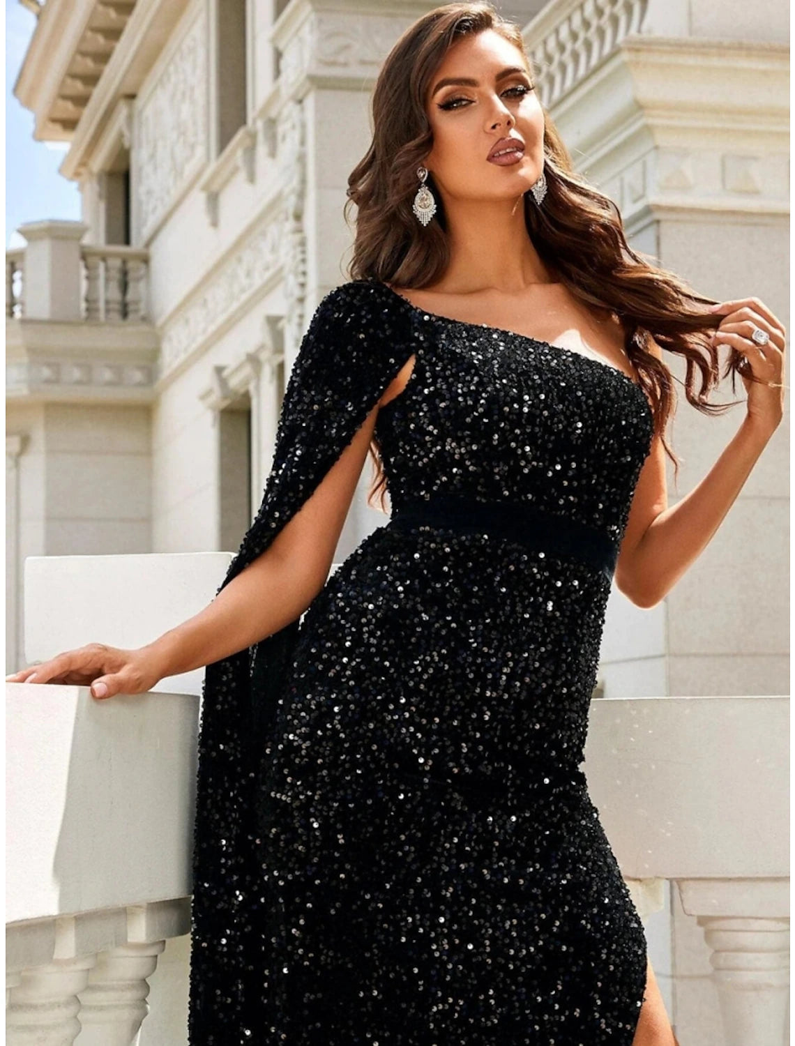 Close-up of the shimmering sequin and glitter detail on the black one-shoulder gown fabric.