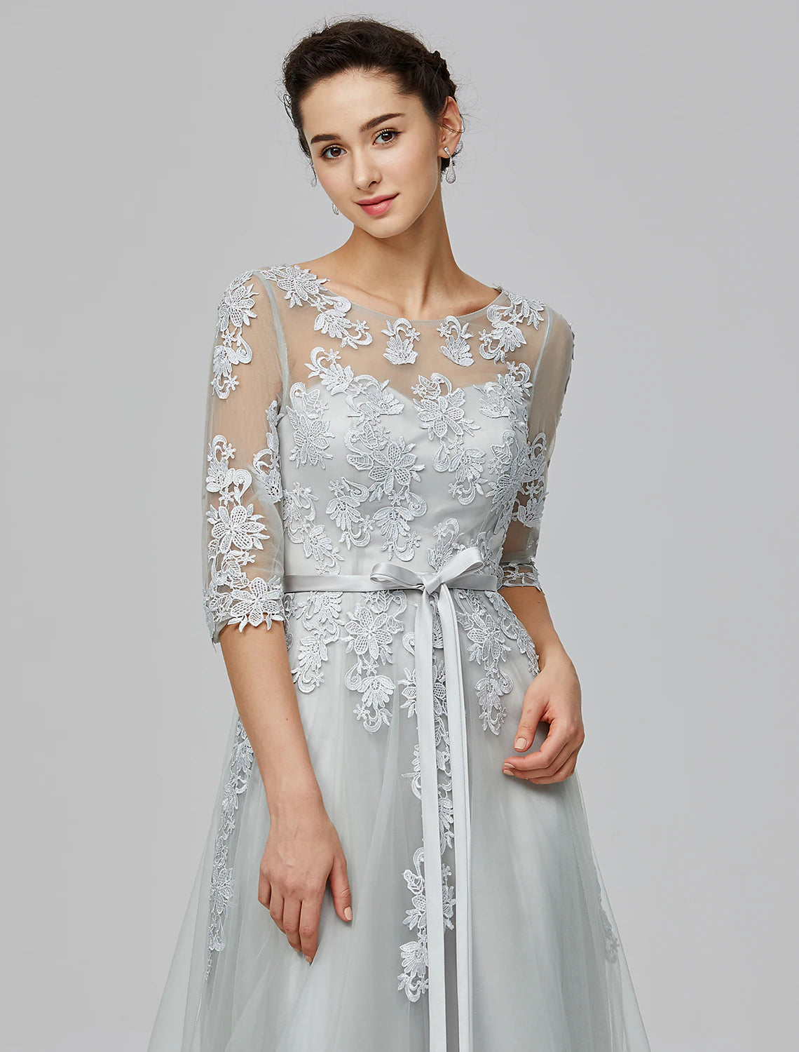 Close-up of the illusion neckline and half sleeves with appliques on a blush gown.