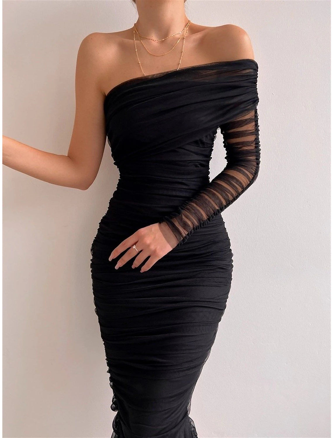Woman wearing a black one-shoulder ruched bodycon midi dress.