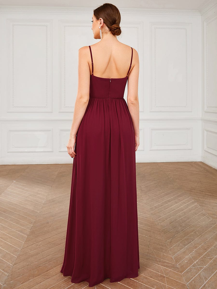 Close-up of the ruched bodice and plunging V-neck of the red chiffon dress.