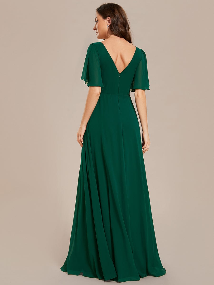 Full length view of a model posing in a dark green chiffon A-line maxi dress.