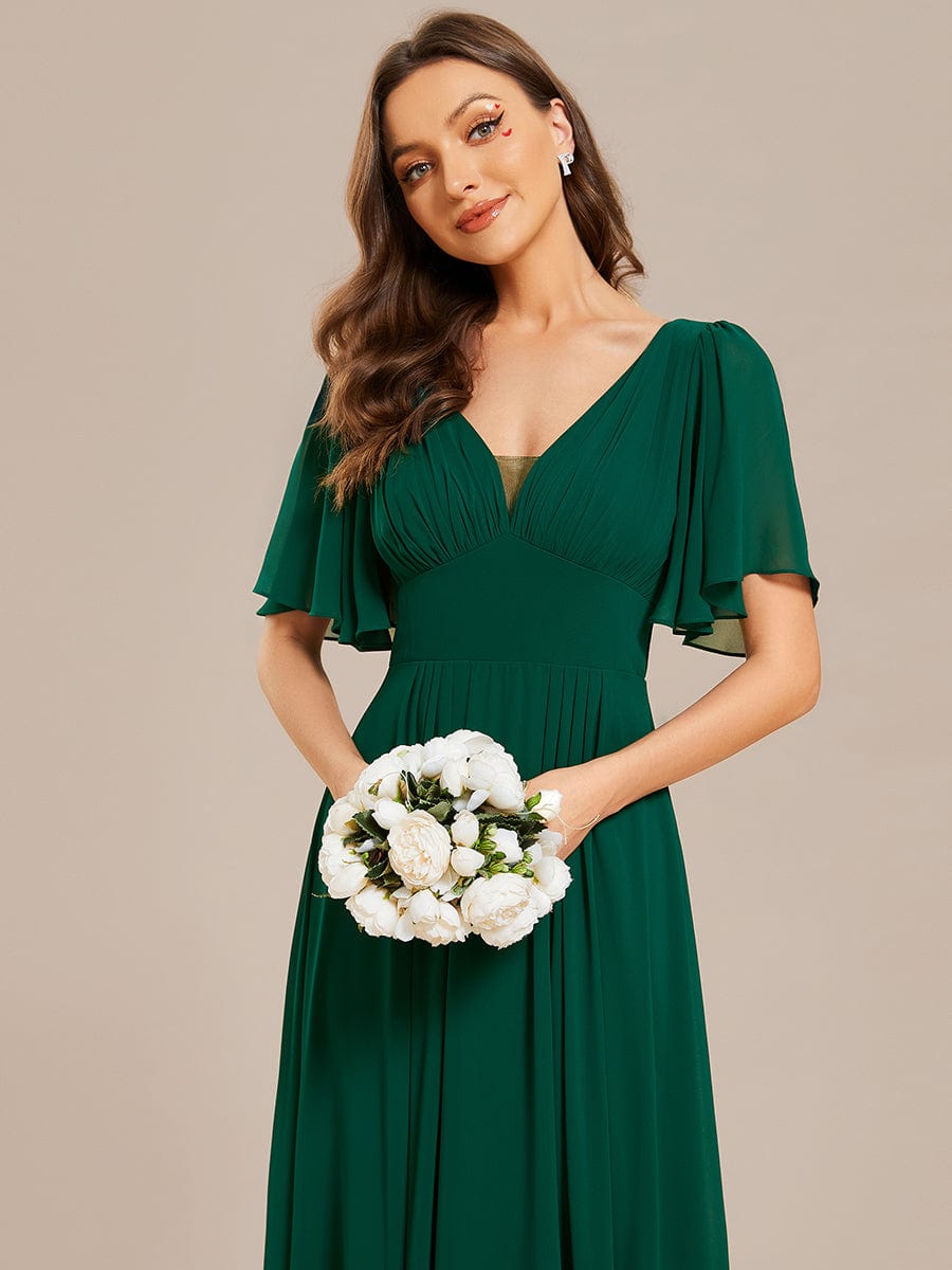 Close-up of the dark green chiffon fabric and short sleeve detail of the dress.