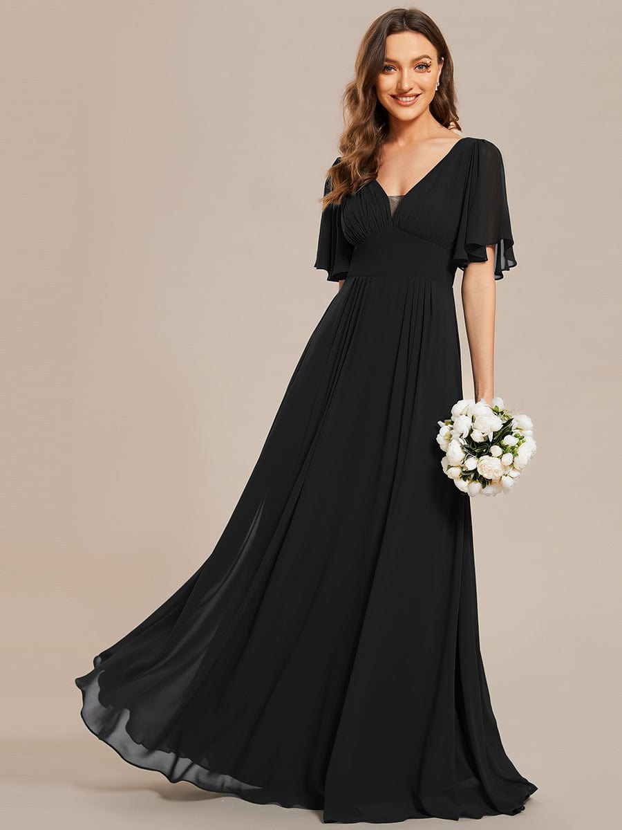 Model wearing a black chiffon A-line maxi bridesmaid dress with short sleeves and empire waist.
