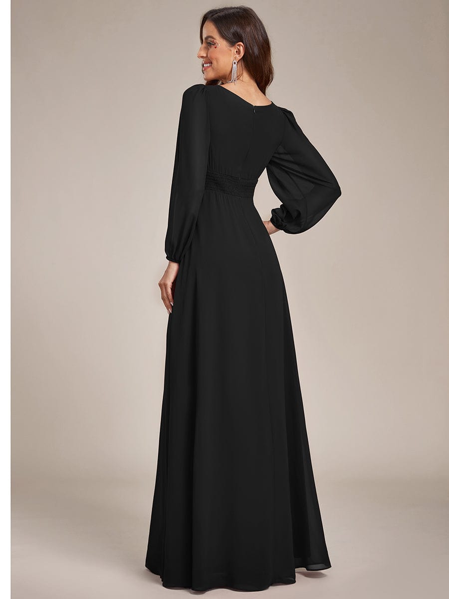 Side view of a woman in a black chiffon empire waist dress with puff sleeves.