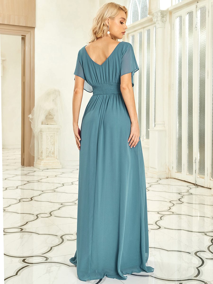 Back view of a woman in a dark blue A-line empire waist chiffon evening dress.