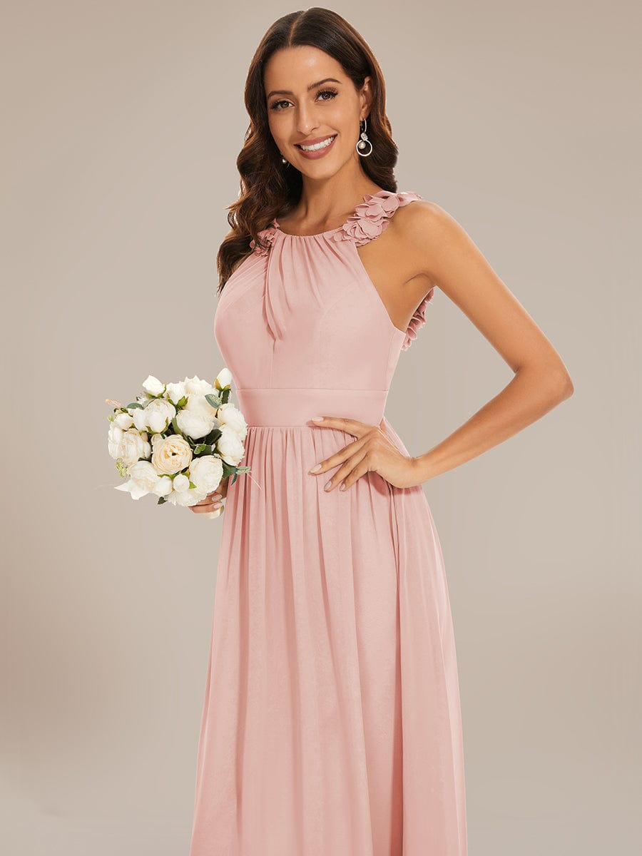 Close-up of floral applique and pleated detail on pink chiffon dress.