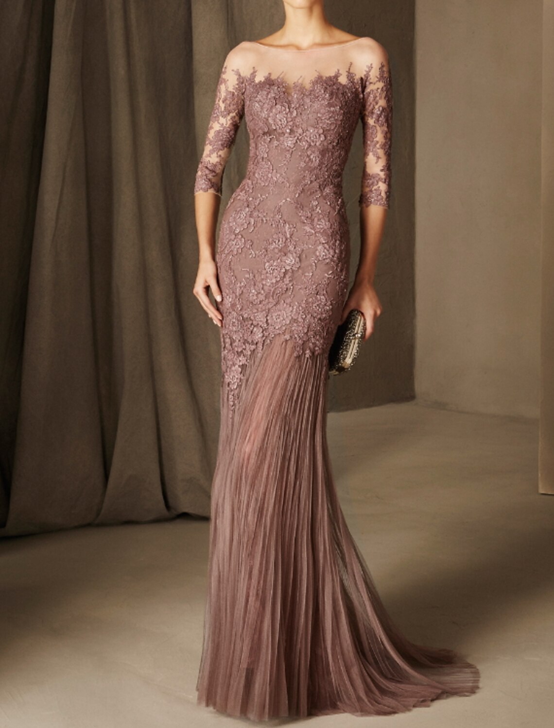 Woman wearing an elegant floral mermaid evening dress with illusion neck and 3/4 sleeves, front view.