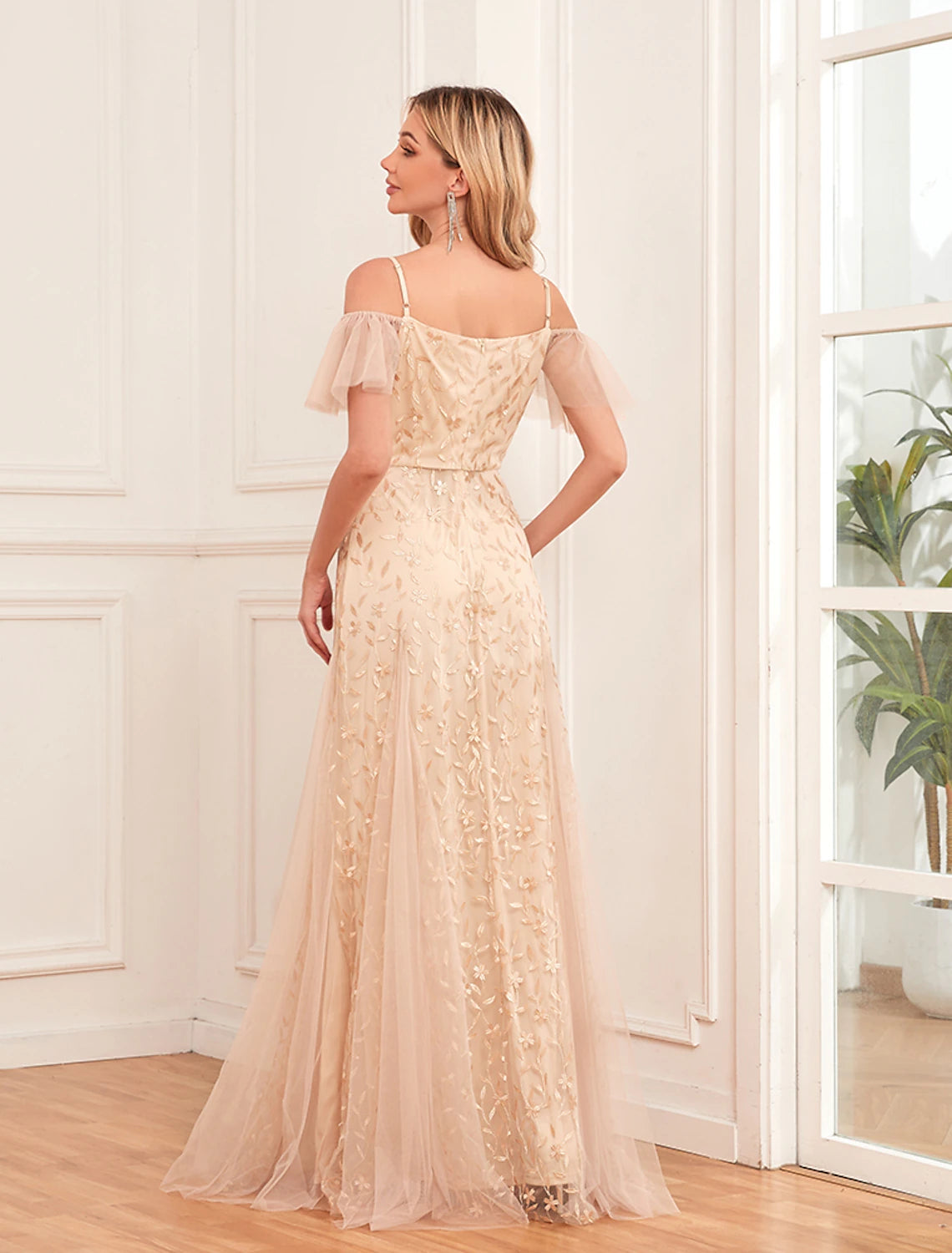 Back view of a woman in a gold floral maxi dress with zipper detail.