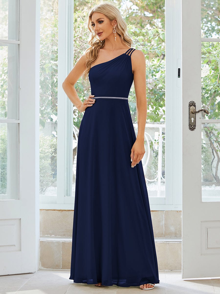 Model posing in a navy blue one-shoulder chiffon dress, showing the flowy skirt.