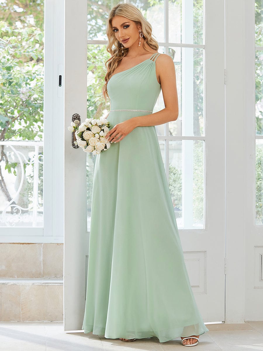 Model wearing a light green flowy chiffon one-shoulder bridesmaid dress.