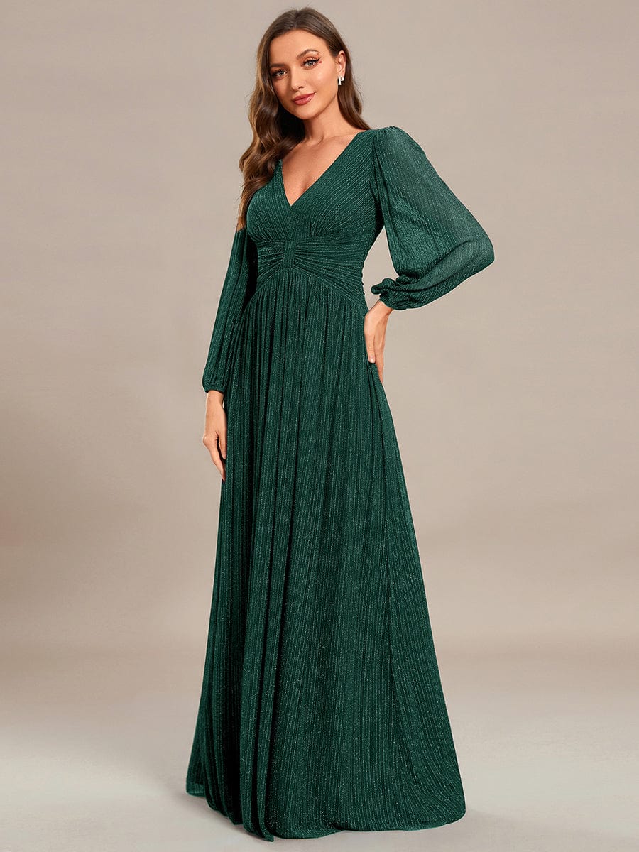 Model wearing a dark green glittery A-line evening dress with long lantern sleeves.