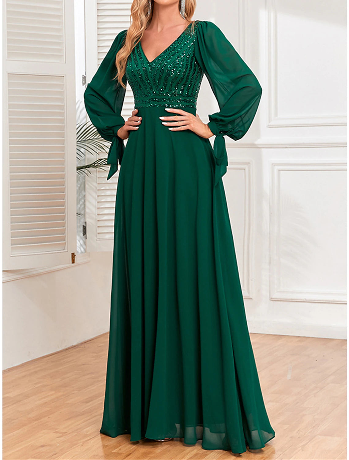 Woman posing in a green sequin long sleeve V-neck maxi dress.