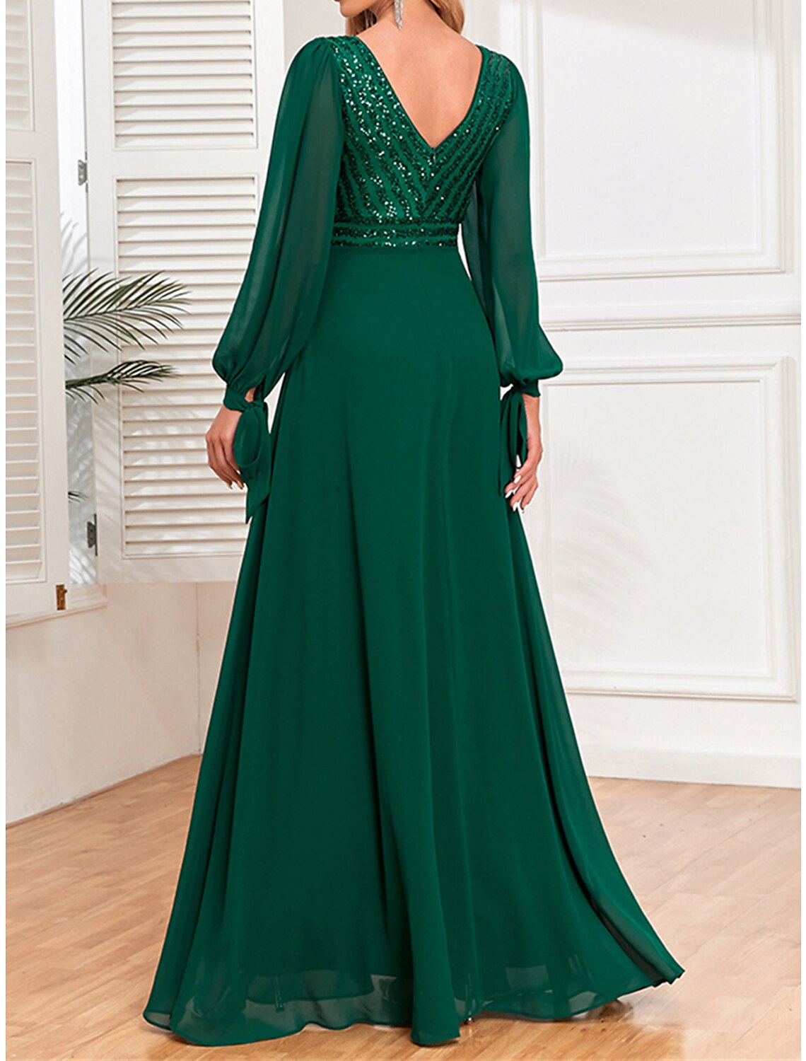 Close-up of a woman in a green sequin maxi dress, showing V-neck and long sleeves.