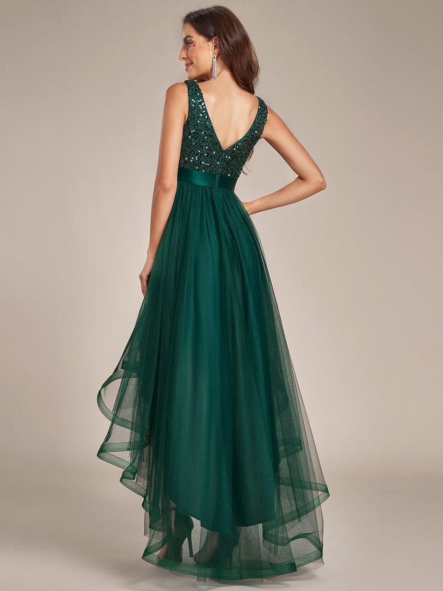 Side profile of a woman in a dark green sequin and tulle high-low dress.