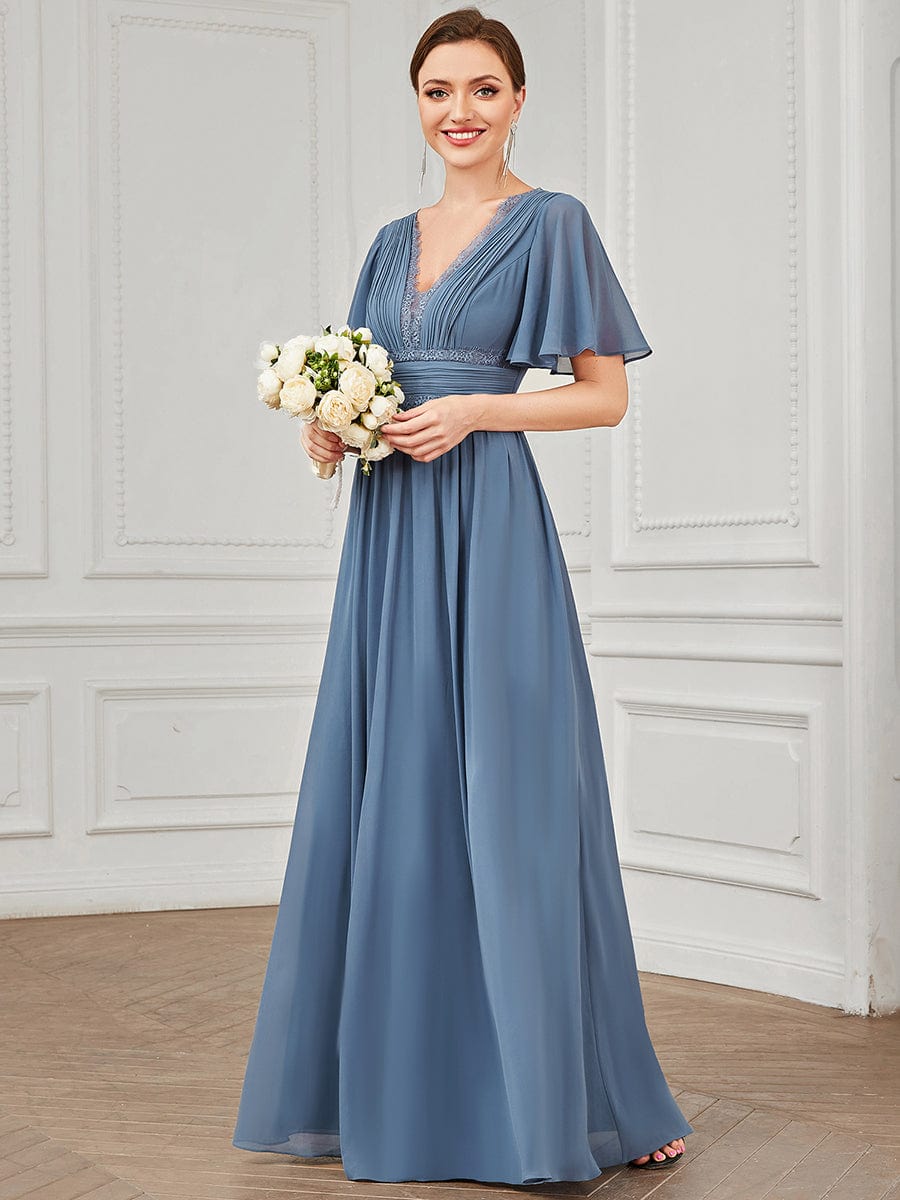 Woman wearing a navy blue lace and chiffon A-line short sleeve bridesmaid dress.