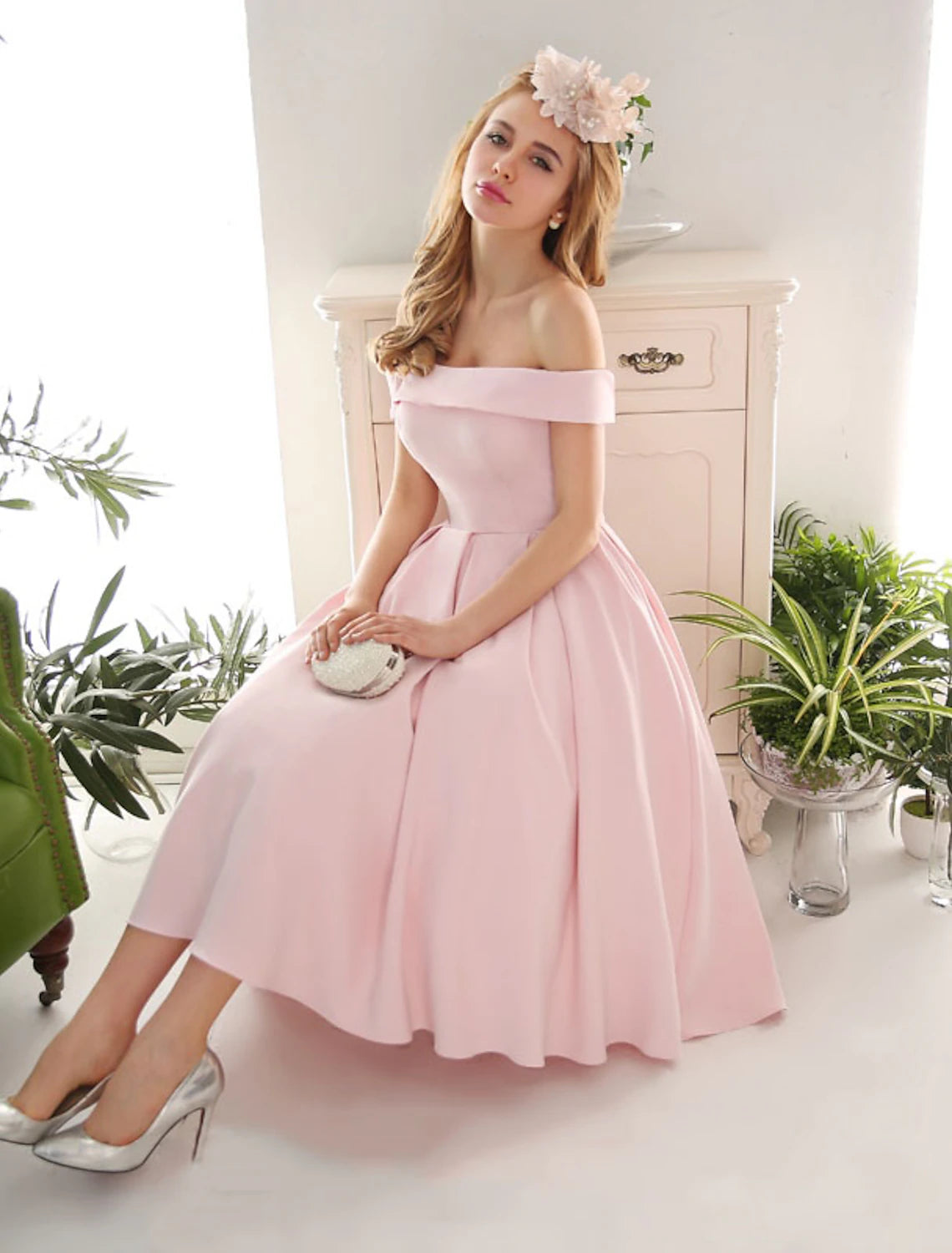 Woman in navy A-line off-shoulder pleated tea-length cocktail dress, front view.