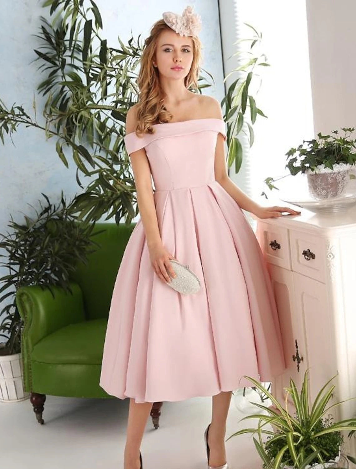 Woman in navy A-line off-shoulder pleated tea-length cocktail dress, side view.