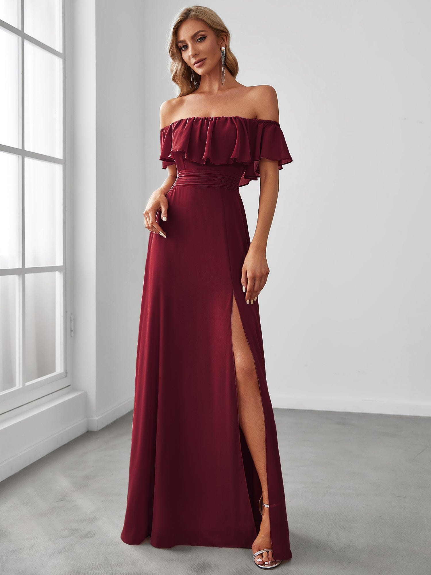 Woman wearing a navy blue off-shoulder ruffle thigh slit A-line bridesmaid dress.