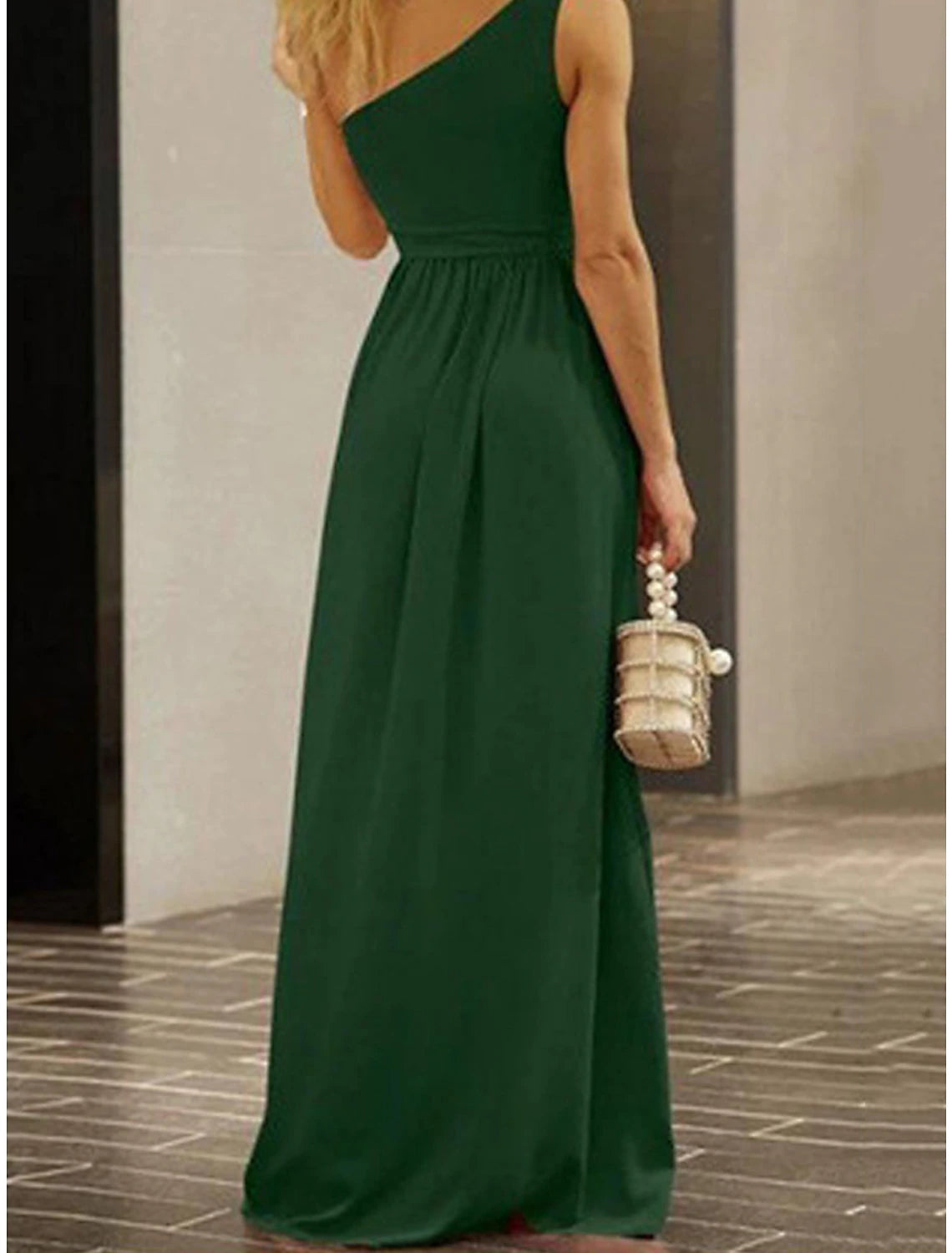 Woman posing in a green one-shoulder backless mini dress.