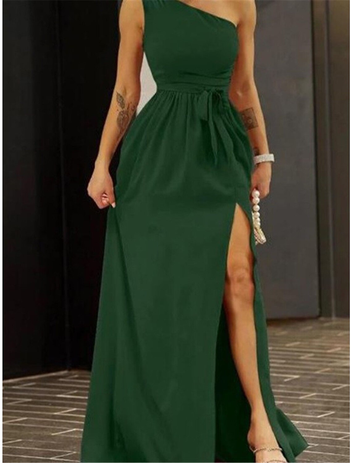 Back view of a woman in a green one-shoulder backless mini dress.
