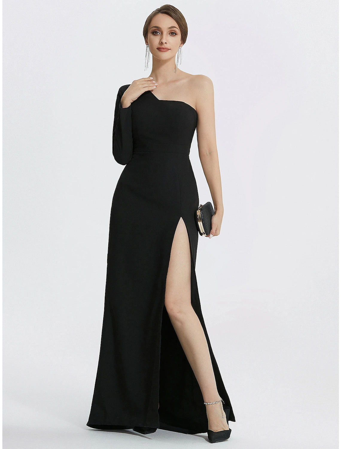 Woman posing elegantly in the black mermaid gown, highlighting the floor-length design and slit.