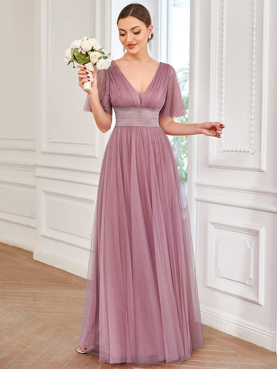 Model in a dark green pleated A-line short sleeve tulle bridesmaid dress.