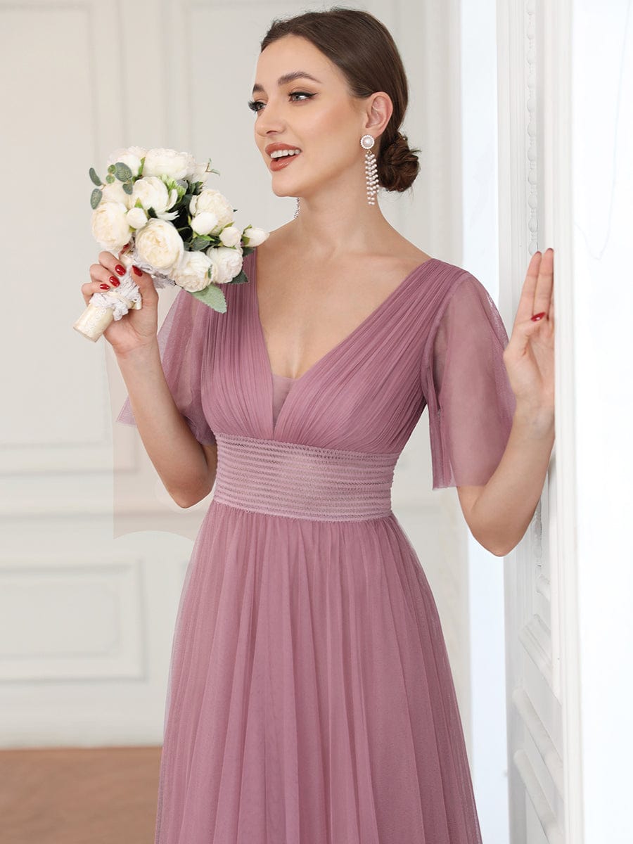 Close-up of the bodice and short sleeve of a dark green pleated tulle dress.