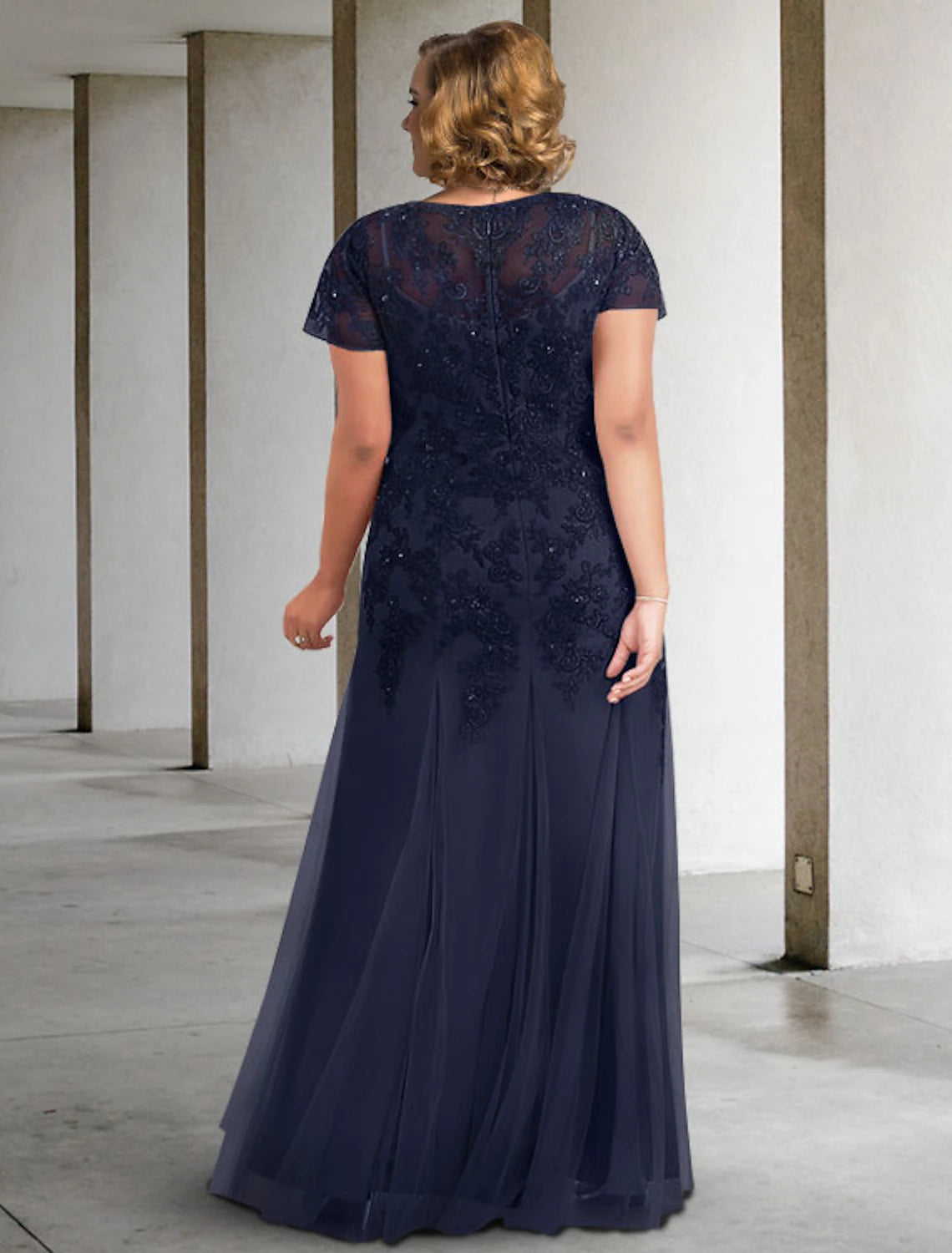 Side view of the elegant plus size A-line Mother of the Bride dress, highlighting pleats and appliques.