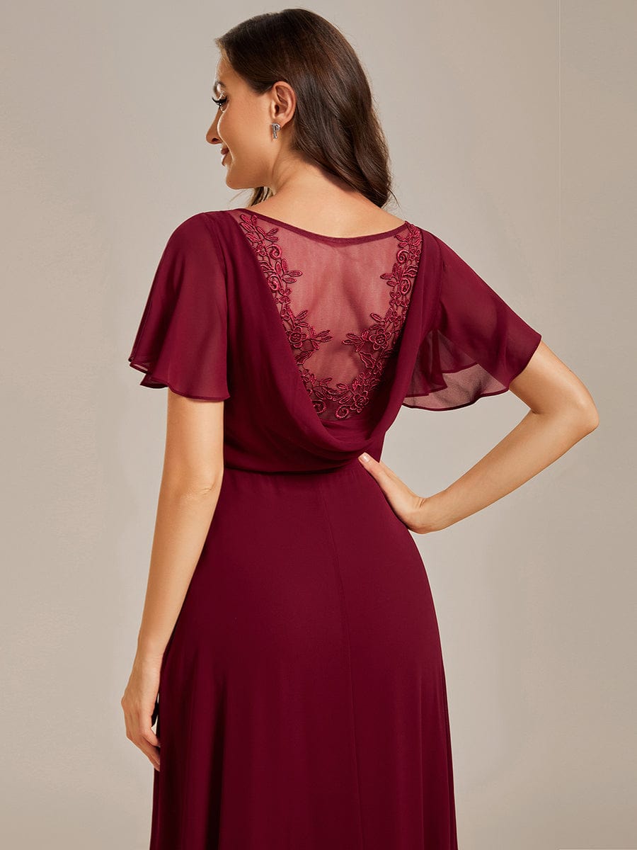 Back view of the red evening dress, highlighting the see-through panel with applique.