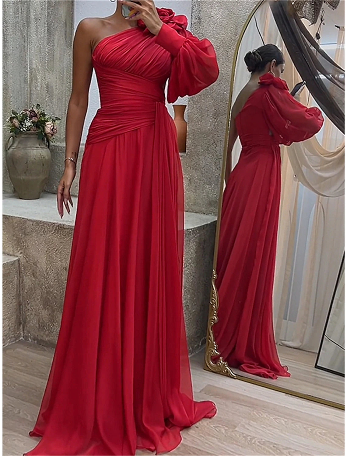 Woman wearing a red ruched one-shoulder long sleeve maxi dress, standing.