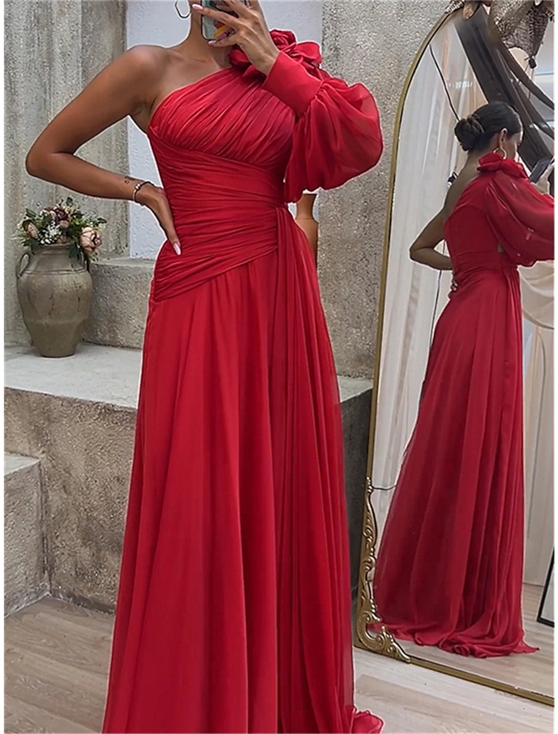 Woman in a red ruched one-shoulder long sleeve maxi dress, side view.