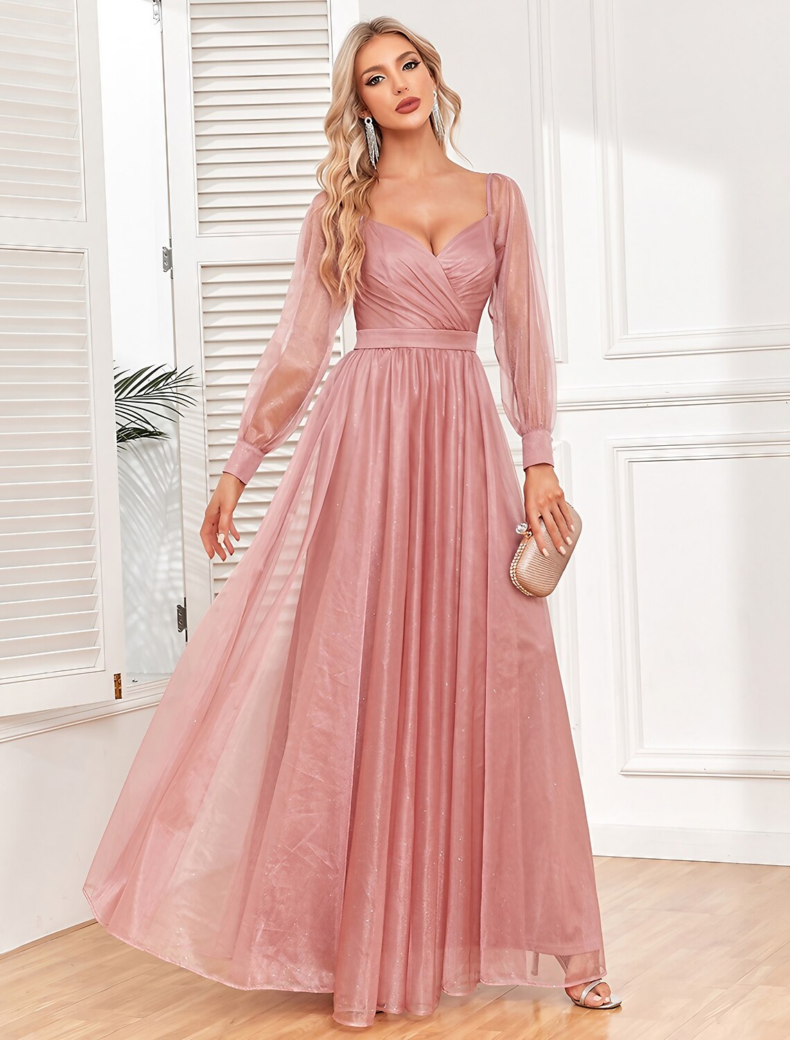Woman wearing a light red ruched V-neck long sleeve maxi dress.
