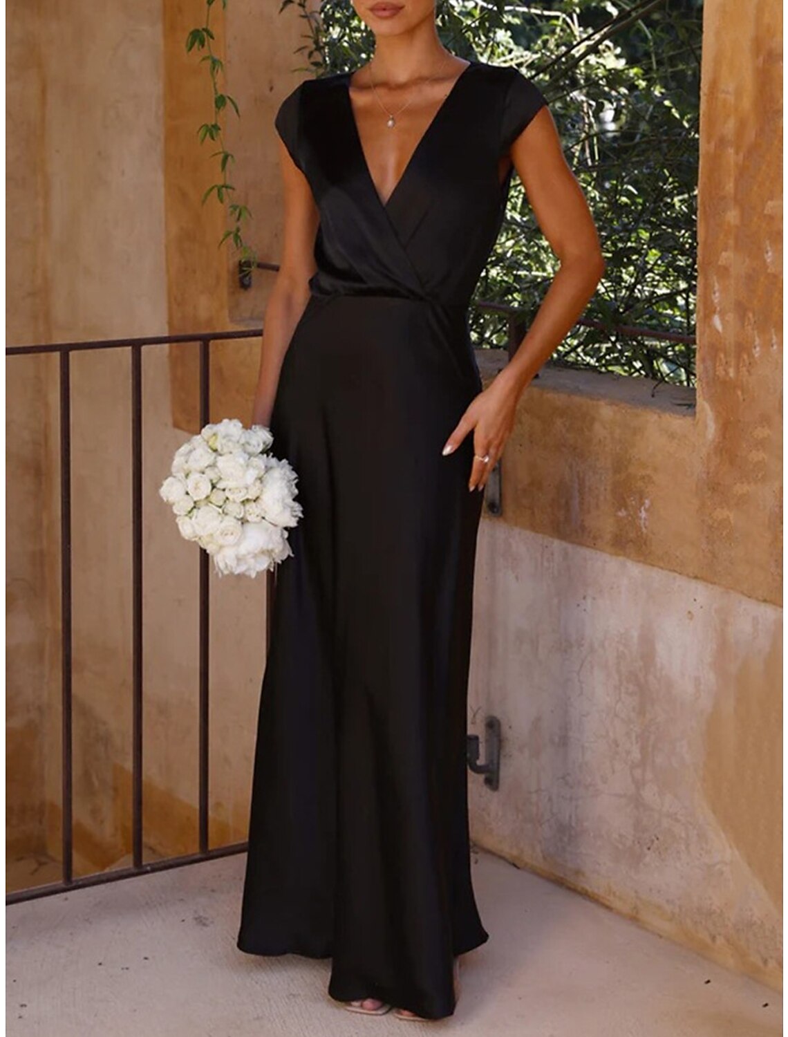 Woman wearing an elegant black ruched V-neck maxi dress.