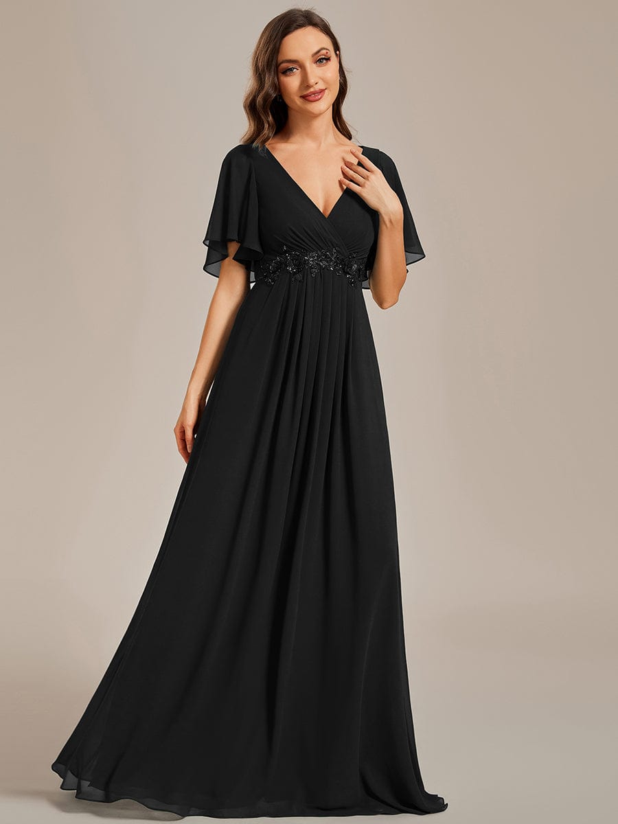 Woman wearing a black Weitese A-line maxi evening dress with ruffles sleeves.