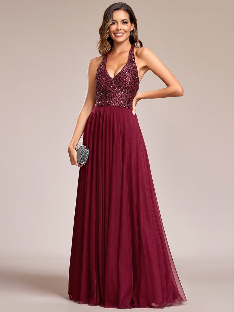 Side view of a model in a red sequin halter neck evening gown.